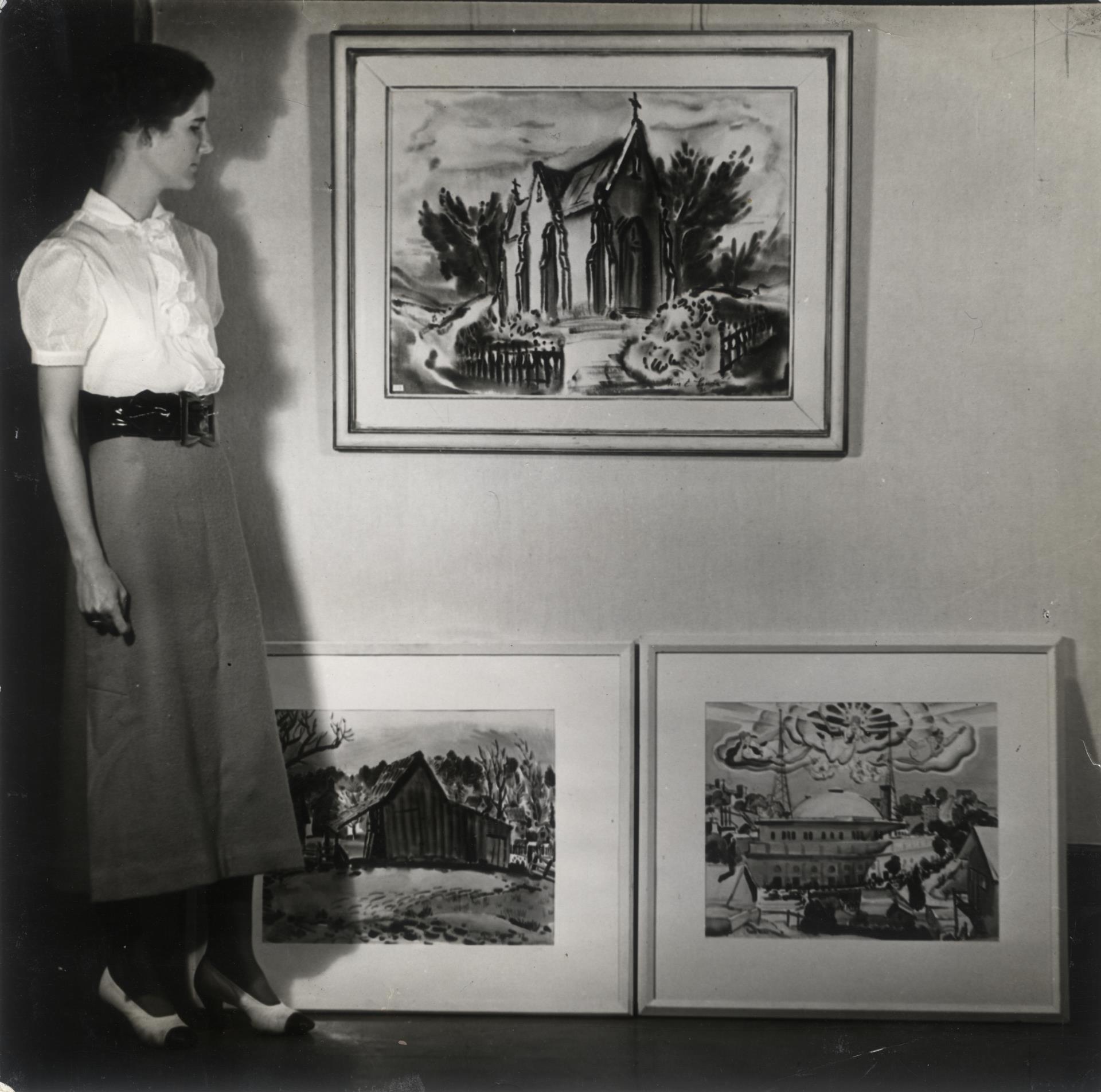 Artist Joan Irving Brandt standing next to her paintings.